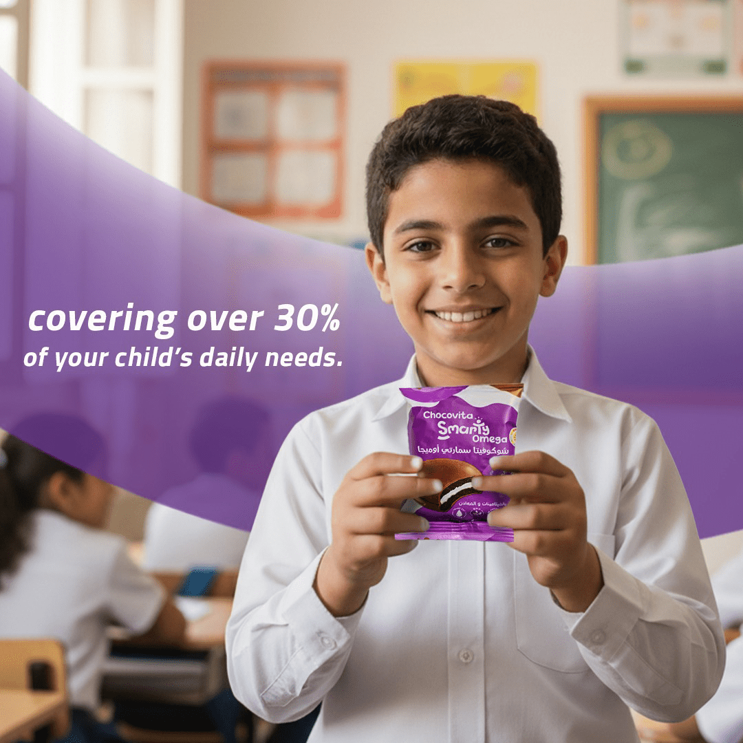 Child holding Chocovita Omega with Vitamin-fortified Marshmallow Chocolate Sandwich in a classroom setting with promotional text overlay.